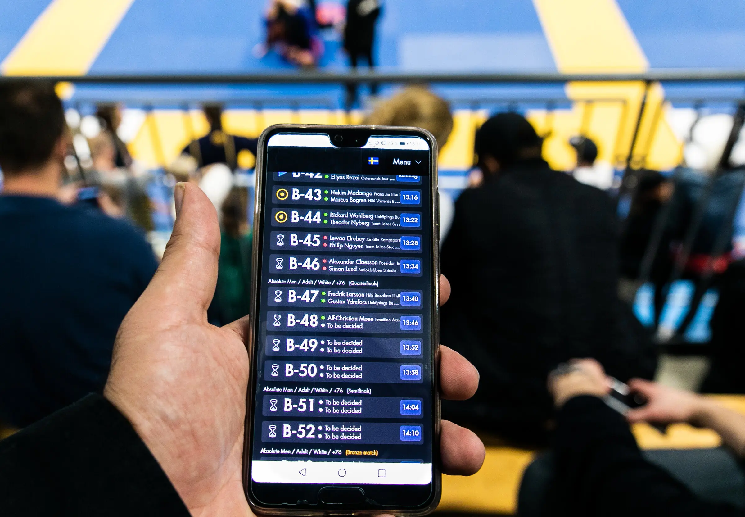 A spectator in the stands following the live schedule on the Smoothcomp app